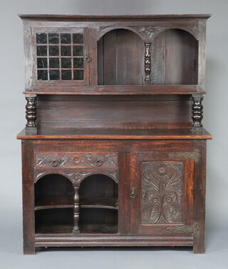 An Art Nouveau carved oak dresser with moulded cornice, the raised back fitted recess and cupboard enclosed by glazed panelled door, the base fitted a drawer above recess and cupboards enclosed by carved panel 188cm h x 152cm w x 53cm d 