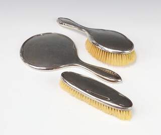 A silver 3 piece dressing table set comprising hand mirror, clothes brush and hairbrush Chester 1928 