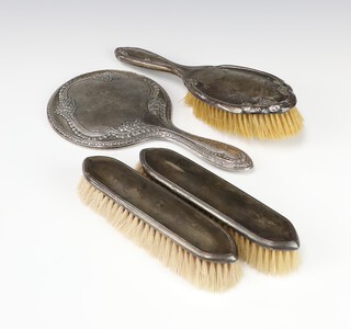 A silver hand mirror Birmingham 1916, a pair of clothes brushes and a hair brush, different makers 