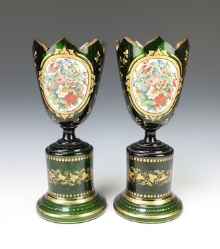 A pair of 19th Century Bohemian green glass vases decorated with panels of scrolling spring flowers, raised on cylindrical bases with scrolling leaves 34cm h  