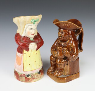 A 19th Century Staffordshire Toby jug in the form of a standing lady 23cm, a brown glazed ditto of a seated gentleman holding a mug of beer 20cm 