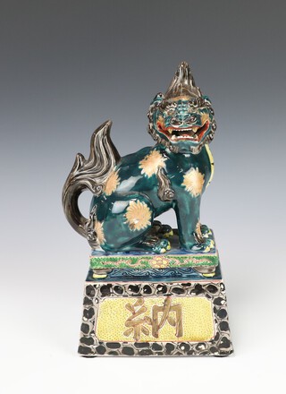 An Antique style Chinese glazed figure of a seated Dog of Fo raised on a plinth 28cm