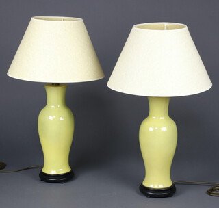 A pair of modern Chinese yellow glazed baluster table lamps on wood stands, 41cm 