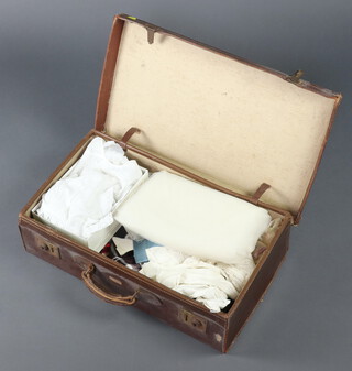 A leather suitcase containing a Victorian broderie anglaise child's dress, 2 small petticoats, pair of white stockings, gentleman's Marcella evening waistcoat, various fabrics, scarves, etc 