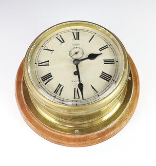 A Smiths ward room style clock, the 18cm painted dial with Roman numerals and subsidiary second hand, contained in a gilt metal case (no key) 16cm h x 31cm diam.  
