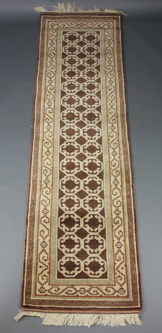 A brown and white ground machine made runner with geometric design 293cm x 82cm 
