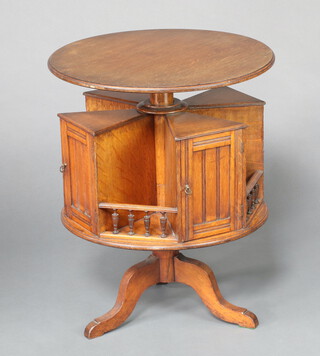 An Edwardian circular oak occasional/work table, the revolving base fitted 4 cabinets enclosed by a panelled door and 4 niches with bobbin turned gallery 69cm x 55cm 