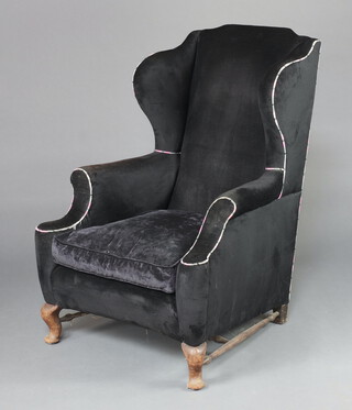 A Georgian style winged armchair upholstered in black material raised on cabriole supports with H framed stretcher 114cm h x 81cm w x 81cm d (seat 36cm x 38cm) 