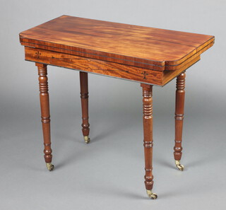 A 19th Century mahogany tea table with ebony inlay, raised on ring turned supports, brass caps and casters, 74cm h x 89cm w x 44cm d 