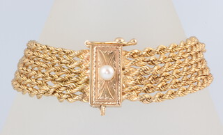 A six strand yellow metal 750 bracelet with a yellow metal stamped 14k  pearl set clasp gross weight 38.5 grams