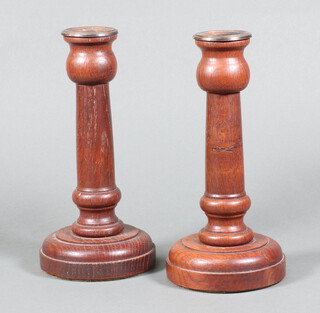 A pair of 1920's turned oak candlesticks with plated sconces on circular bases 23cm,  base marked Made from the oak of a 14th Century roof Crowbridge Church Wybert Thomas 