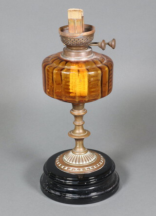 A Victorian oil lamp with amber glass reservoir raised on an embossed gilt metal base with ceramic socle (no shade or chimney) 36cm h   