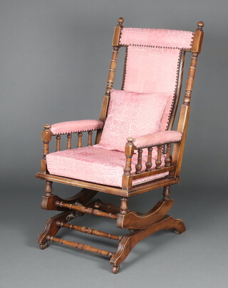 An American beech framed rocking chair with spindle turned decoration, upholstered in pink material 111cm h x 56cm w x 65cm d 