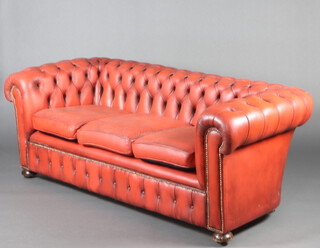 A 3 seat Chesterfield upholstered in red buttoned material, raised bun supports 73cm h x 192cm w x 88cm d (seat 140cm x 52cm) 