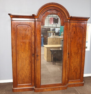 A Victorian mahogany triple wardrobe with arched cornice, the centre section fitted 4 trays above 3 long drawers and enclosed by an arched mirrored door, flanked by cupboards with hanging sections enclosed by panelled doors  236cm h x 214cm w x 63cm d 