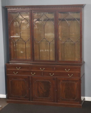 An Edwardian mahogany triple library bookcase with moulded cornice, the shelved interior enclosed by astragal glazed doors, the base fitted 3 short and 1 long drawers above triple cupboard, raised on a platform base 235cm h x 182cm w x 53cm d  