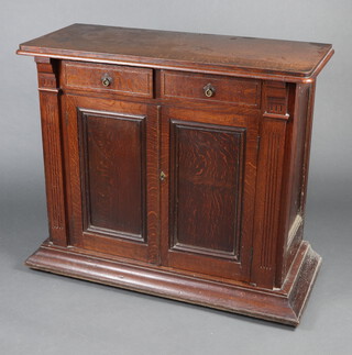 A Victorian oak cabinet fitted 2 drawers above a double cupboard enclosed by a pair of panelled doors and fluted columns to the sides, 94cm h x 107cm w x 47cm d 