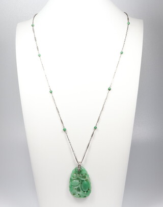 A good carved jade apple green pendant decorated with fruits on a white metal diamond set loop, on a white metal 18k chain, set with 10 small jade beads, the pendant 35mm, the chain 66cm