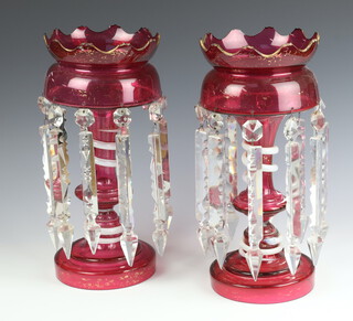 A pair of Victorian cranberry lustres with waisted stems and clear drops 35cm 