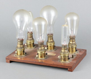 A collection 6 vintage light bulbs mounted on a wooden base 