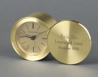 A Tiffany and Co quartz travelling alarm clock in a cylindrical case with gilt dial marked Tiffany and Co, the outer case marked Avis Inc. Levergaged Lease December 1988 4cm x 6cm 