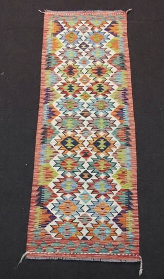 A white, turquoise and orange ground Chobi Kilim runner with 24 stylised medallions to the centre 193cm x 65cm 