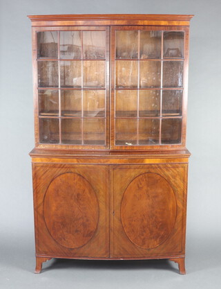 Heal's, a Georgian style bow front display cabinet on cabinet with moulded cornice, the upper section fitted adjustable shelves, the cross banded base enclosed by a pair of panelled doors, raised on bracket feet, bears Heal's whitespot label to inside door, 200cm h x 122cm w x 44cm d 