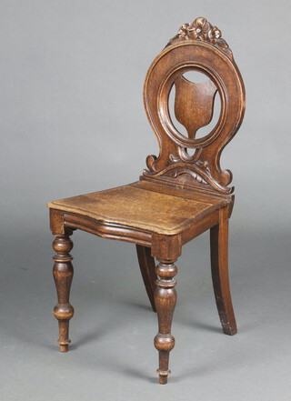 A Victorian oak hall chair with circular shaped back and solid seat of serpentine outline, raised on turned supports 91cm h x 44cm w x 36cm d 