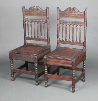 A pair of 17th Century style carved oak hall chairs with spindle turned backs and solid seats, raised on turned supports 105cm h x 45cm w x 44cm d 