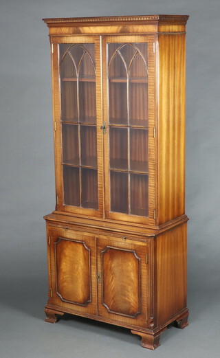 A Georgian style mahogany display cabinet the upper section with moulded and dentil cornice fitted shelves enclosed by astragal glazed panelled doors, the base fitted a brushing slide above double cupboard enclosed by panelled doors, raised on ogee bracket feet 175cm h x 75cm w x 40cm d 