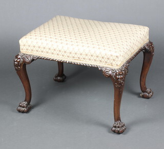 A 19th Century Georgian style rectangular carved mahogany stool raised on cabriole supports, the knees carved masks, having an upholstered seat, 48cm h x 63cm w x 51cm d 