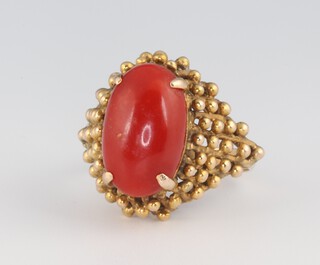 A yellow metal 18ct cabochon coral (14mm by 8mm) set ring, size O 1/2, 6.9 grams 