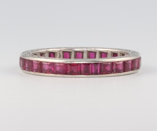 A white metal princess cut ruby eternity ring, comprising 22 princess cut stones each 0.01ct, (0.25ct in total), 2.6 grams, size P 1/2