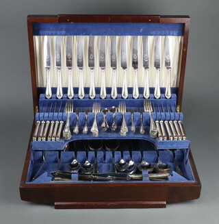 An Art Deco mahogany canteen containing a set of plated cutlery for 12 comprising 12 dinner knives, 12 dinner forks, 12 dessert knives, 12 dessert forks, 12 cake forks, 11 tea spoons, 8 soup spoons, 8 dessert spoons, 4 serving spoons, 3 piece carving set, all contained in a cantilever canteen 