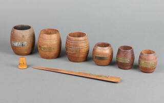Six First World War turned teak and brass match holders, formed from teak of various war ships - HMS Warspite, HMS Iron Duke, HMS Ormonde, HMS Ganges, HMS Valiant and HMS Queen Elizabeth, together with a wooden paperknife from Jericho's flag ship, a wooden thimble marked USS North Carolin Battleship Memorial  