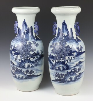 A pair of 18th Century style blue and white baluster vases decorated with extensive landscape scenes with figures at pursuits, having geometric handles 57cm 