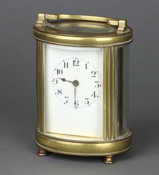 A 20th Century French 8 day carriage timepiece with enamelled dial Arabic numerals contained in an oval gilt metal and glass case, with inscription to the top, raised on bun feet, with key,  12cm h x 9.5cm w x 7cm d  