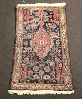 A Persian red and blue ground rug with central medallion 146cm x 79cm