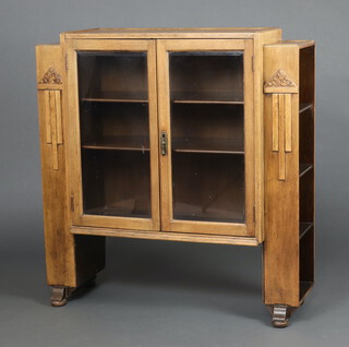 A 1930's Art Deco light oak display cabinet, the centre section fitted shelves enclosed by glazed panelled doors and 4 open shelves to the sides 104cm h x 131cm w 32cm  d 