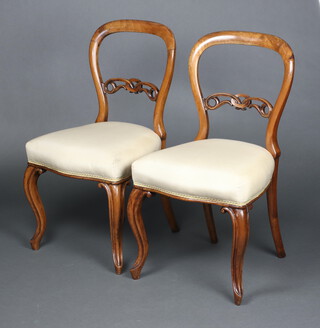 A pair of Victorian carved and pierced walnut ballon back dining chairs with overstuffed seats, raised on cabriole supports 85cm h x 47cm w x 43cm d 