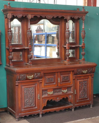An Edwardian heavily carved walnut chiffonier sideboard the raised back fitted 3 arched plate mirrored panels flanked by columns, the centre fitted a cupboard above drawer with recess, flanked by drawers above cupboard  216cm h x 183cm w x 61cm d 