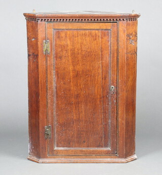 An 18th Century oak hanging corner cabinet with moulded cornice, fitted shelves enclosed by a panelled door with brass H framed hinges 96cm h x 74cm w x 44cm d  