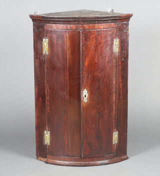 An 18th Century mahogany bow front hanging corner cabinet, fitted shelves enclosed by crossbanded panelled doors with H framed hinges 97cm h x 95cm w x 44cm d  
