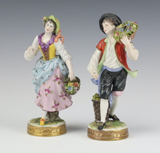 A pair of 20th Century German figures of a lady and gentleman carrying flowers on raised circular bases 19cm 