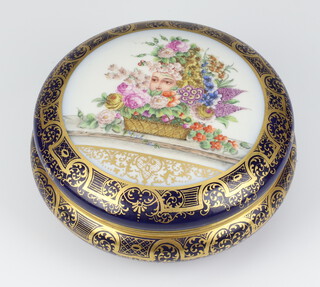 A modern Continental circular blue ground box and cover the lid with a mask and basket of flowers 18cm 