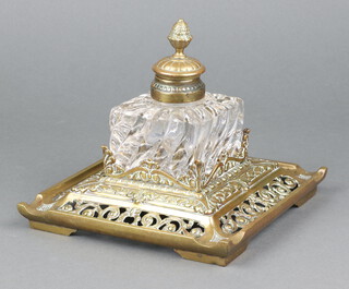 A Victorian square cut glass inkwell with hinged lid, raised on a pierced brass base marked CS 12cm h x 18cm w x 18cm d 