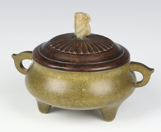 A Chinese gold speckle bronze censer of squat form with loop handles raised on tapering tripod supports, having a carved hardwood cover surmounted with central hardstone finial of a boy, Xuande mark to base, censer (without cover) 17cm high x 7cm wide, weight 1291g (without cover) 1492g (with cover)