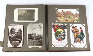 A red postcard album containing 12 First World War embroidered postcards, various black and white and coloured postcards