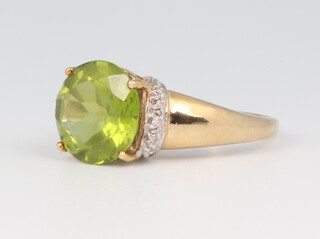 A yellow metal 375 brilliant cut peridot ring with diamond set shoulders, the centre stone 4.30ct, 4.4 grams, size M 1/2 together with a Rocks & Co certificate of authenticity 