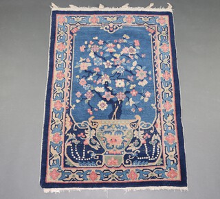 A 1930's blue ground and floral patterned Chinese rug depicting an urn of flowers 137cm  x 95cm